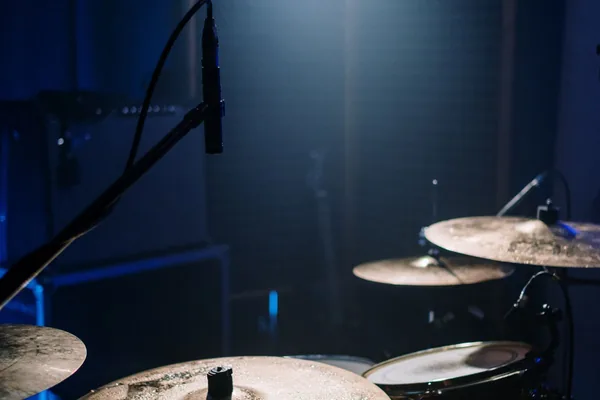 Acoustic drum kit lit by warm light in a darkened studio
